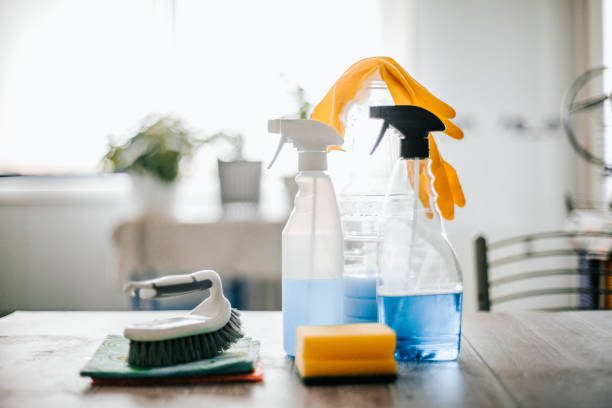 Een hand in een groene handschoen reinigt een kraan met een schoonmaakdoek.