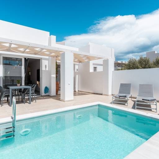 Moderne villa met privézwembad, ligstoelen en heldere lucht.